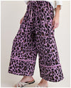 Purple leopard print pants worn by a person on a plain background