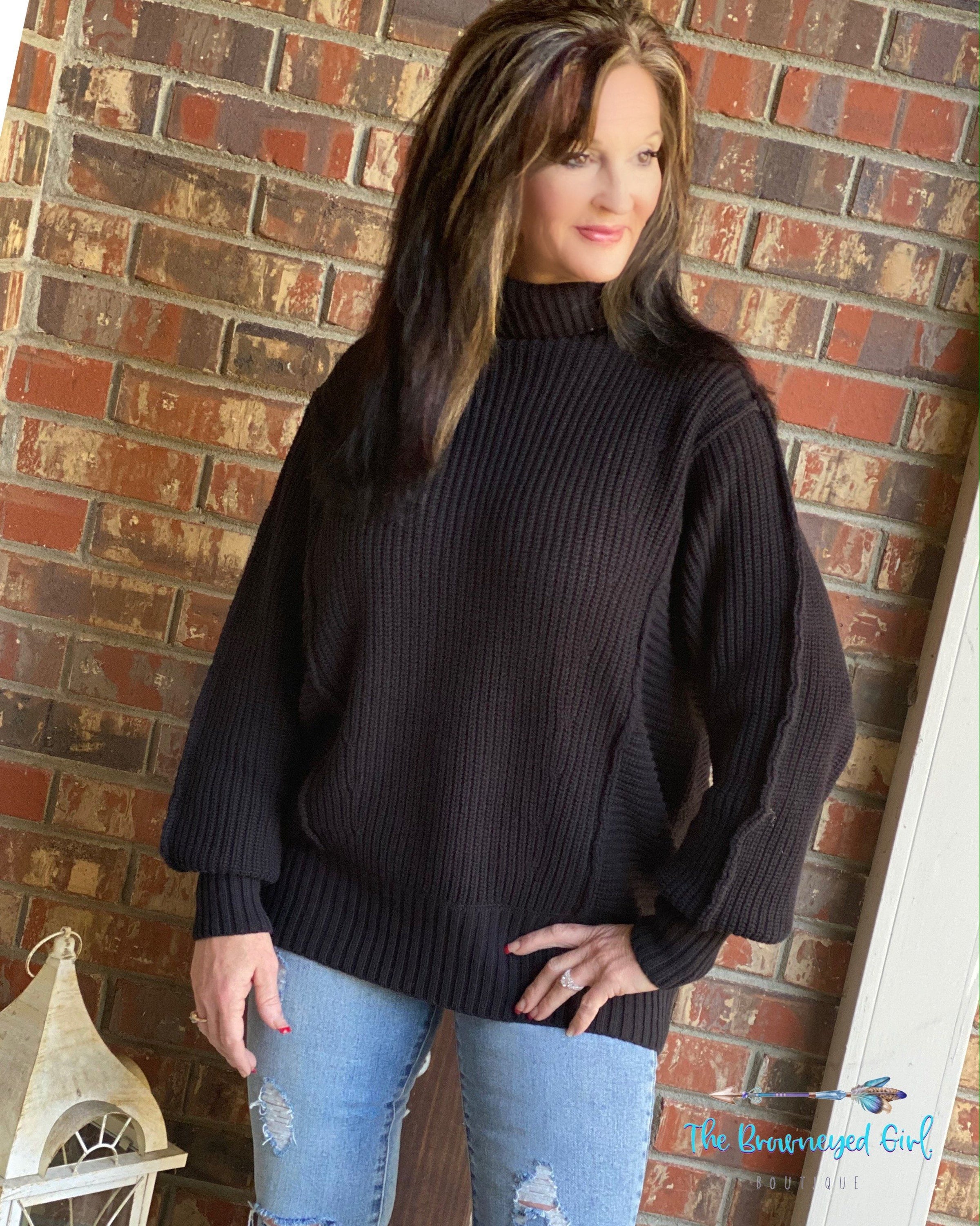 Woman wearing a block heavy weight slightly over sized sweater. Loose fitting neck.