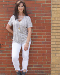 Woman wearing a short sleeve  grey and white snake skin v-neck top. Material is soft and stretchy. Model wearing size large. Thebrowneyedgirl boutique