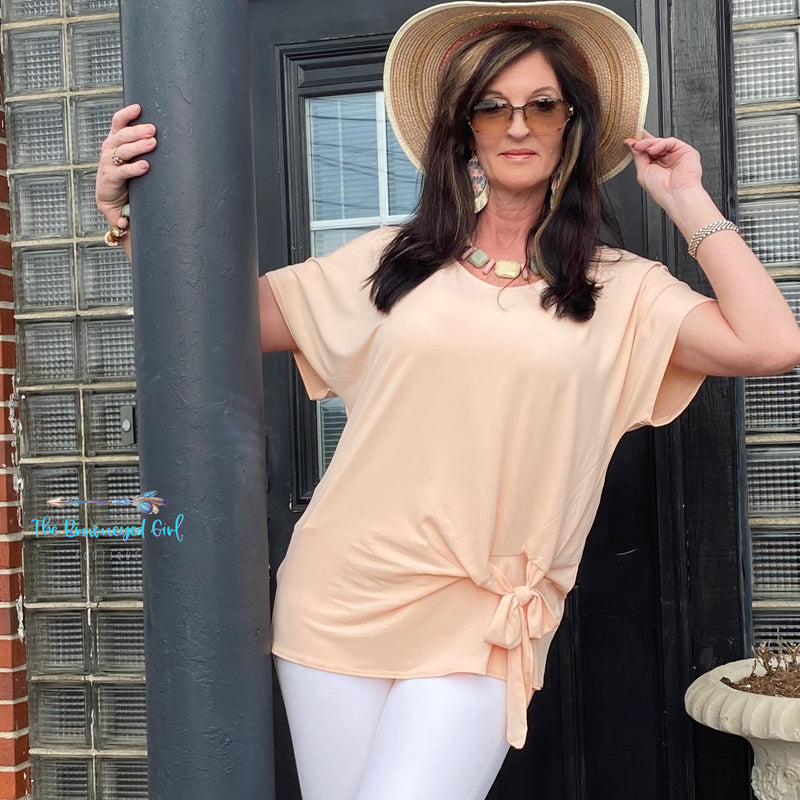 Woman wearing a dressy casual light peach short sleeve top with front tie. This top is super cute soft and light weight