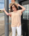 Woman wearing a light peach colored short sleeve top. With a crew neck line and front tie . This top is dressy casual  light weight fits true to size.
